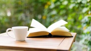 屋外のテーブルに書籍とコーヒー